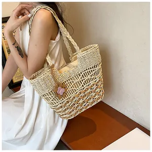 Dettaglio della borsa tote in paglia intrecciata a mano con motivi traforati e ciondolo