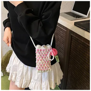 Close-up of handmade crochet tulip phone bag with pearl pendant and knit strap