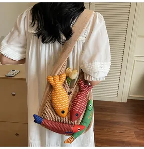 Detail of beige knit tote bag featuring colorful fish charms and soft woven texture