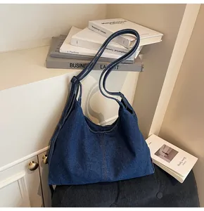 Detailed view of dark blue denim tote bag with brown contrast stitching and wide strap