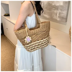 Dettaglio della borsa tote in paglia intrecciata a mano con motivi traforati e fiori
