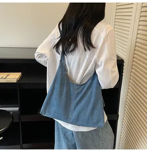 Lifestyle shot showing the drape of a casual light blue denim tote bag worn on shoulder