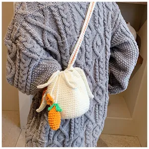 Détail d'un sac seau blanc tricoté main avec breloque carotte et motifs floraux