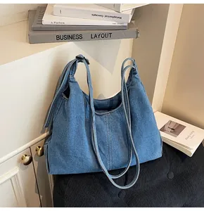 Detail of blue denim hobo bag with vertical stitching on a black corduroy cushion