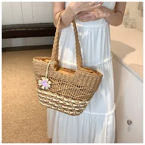 Dettaglio della trama della borsa tote in paglia intrecciata con ciondolo floreale