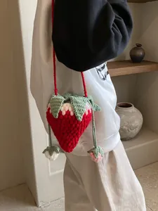 Handmade red crochet strawberry crossbody bag with green leaf detail and knit shoulder strap