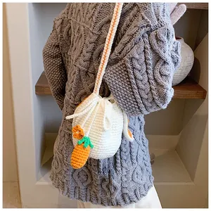 Détail du sac seau au crochet blanc avec texture faite main et breloque carotte mignonne