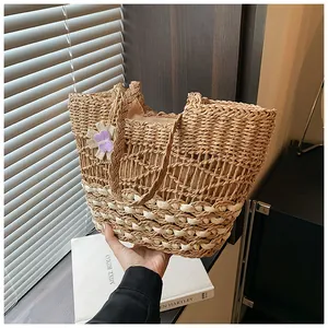 Dettaglio della borsa tote in paglia intrecciata a mano con cuciture bicolore