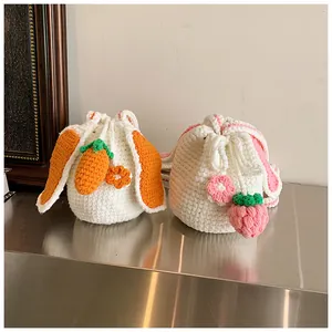 Détail de sacs seaux tricotés main avec oreilles de lapin et breloques fraise carotte