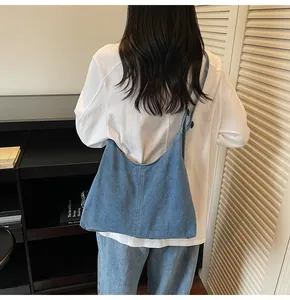 Blue denim hobo bag featuring contrast stitching and wide shoulder strap on model