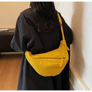 Detail view of yellow crescent nylon crossbody bag with woven zipper pull on model