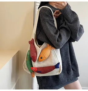 Detail of white crochet tote bag featuring colorful 3D fish charms and woven texture