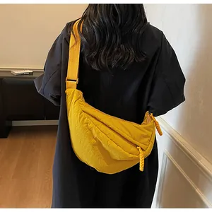Detailed close-up of a bright yellow crescent bag with texture and woven zip pullers