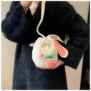 Détail d'un sac seau fait main au crochet blanc avec oreilles de lapin et breloque fraise