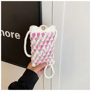 Detail of hand-knitted tulip phone bag featuring a handmade with love wood button