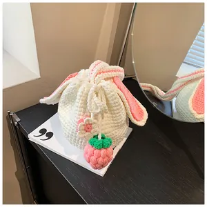 Détail du sac seau au crochet avec oreilles de lapin, breloque fraise et accents floraux