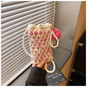 Detailed close-up of a handmade crochet tulip crossbody phone bag with a pearl flower charm