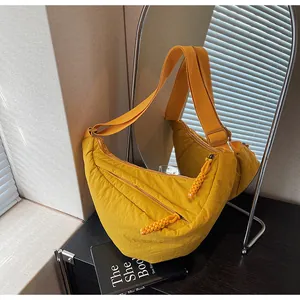 Detail of a bright yellow crescent bag with textured nylon and wide adjustable strap