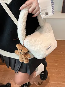 White faux fur bucket bag with plush teddy bear pendant and woven brand label