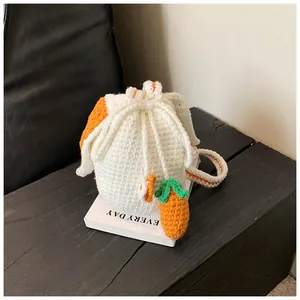 Détail d'un sac seau tricoté main avec oreilles de lapin et pendentif carotte