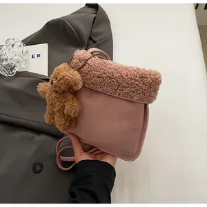 Detail of pink faux suede crossbody bag with fluffy fleece trim and cute brown bear charm