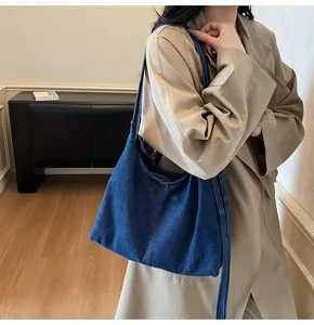 Detailed view of dark blue denim tote bag texture and stitching on a model outfit