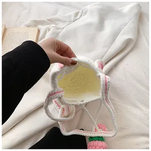 Détail du sac seau blanc au crochet fait main avec breloque fraise rose et texture tricotée