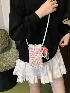 Crochet tulip mini crossbody bag with pink strawberry charm shown on female model