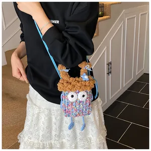 Détail du sac monstre bleu en tricot avec grands yeux blancs et nœuds marron