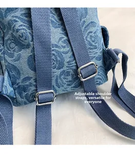 Detail of adjustable strap and silver buckle on denim backpack with 3D rose pattern