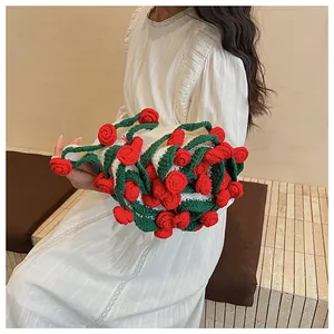 Detail of handmade crochet handbag with 3D red roses and green leaves on white base
