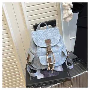 Detail of floral denim mini backpack with leather straps and colorful bead tassels