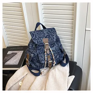 Close-up of denim mini backpack featuring vintage 3D rose patterns and beaded tassel charm