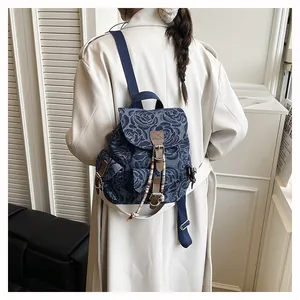 Macro shot of retro denim backpack featuring rose jacquard fabric and leather strap details