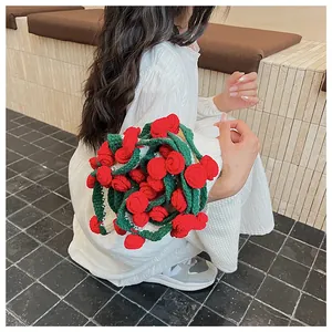Detail of a handmade 3D red rose crochet tote bag held by a model in a white dress