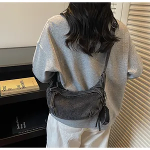 Dettaglio borsa a mezzaluna in denim grigio vintage con mini borsellino e tracolla