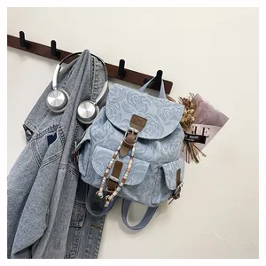 Detail of vintage denim backpack with rose jacquard, leather straps and beaded drawstring