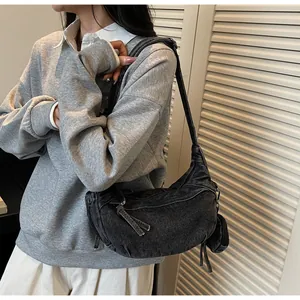 Dettaglio della borsa hobo in denim grigio con mini pochette abbinata su una modella