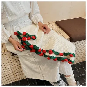 Detailed macro of handmade crochet white blanket with 3D red roses and green leaves