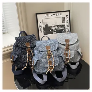 Detailed view of three vintage denim backpacks with rose floral jacquard patterns on a table