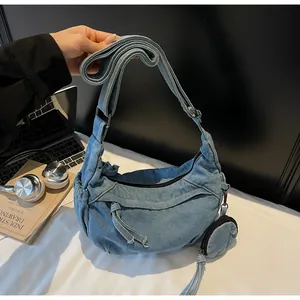 Dettaglio della borsa a tracolla in denim blu con tracolla larga e portamonete rotondo