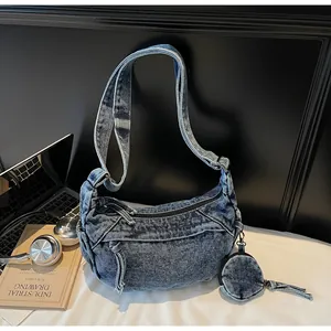 Detail of washed denim crescent bag with circular coin purse and industrial hardware