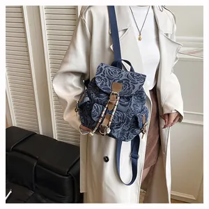 Detail of denim backpack with rose jacquard pattern and leather buckle closure