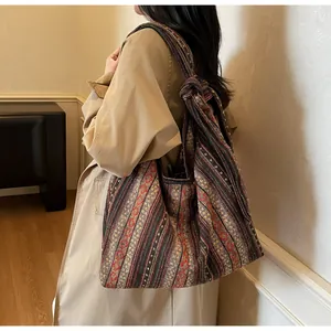 Detail of bohemian woven tote bag with red and green geometric patterns and knotted straps