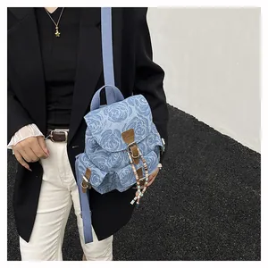 Detailed macro view of denim backpack with rose jacquard pattern and leather strap buckles