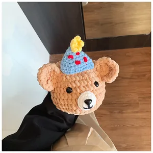 Close-up of handmade crochet bear charm with blue polka dot party hat and yellow star