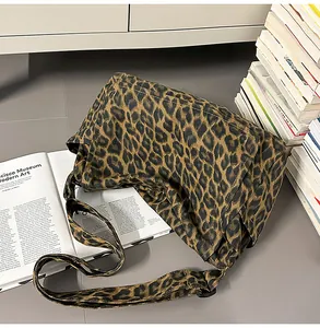 Close-up of leopard print canvas bag with wide strap against a stack of art books
