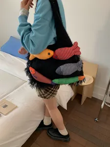 Sac fourre-tout noir en peluche avec poupées de poissons colorées porté par un modèle