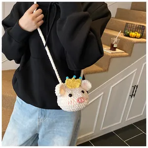 Detail of a handmade crochet pig mini bag with a crown on soft white knitted texture