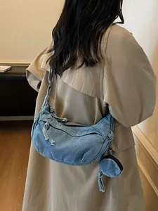 Borsa hobo vintage in denim blu con portamonete indossata su un trench color kaki
